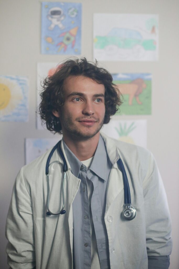Smiling pediatrician in a bright office adorned with children's artwork, wearing a stethoscope.